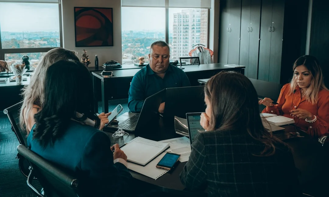 Two businessmen analyze stock market data using a smartphone and laptop in a modern office setting.